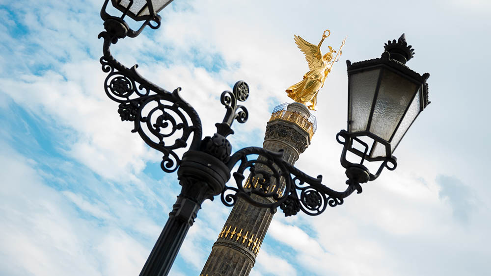 Goldene Statue der Siegessäule zwischen historischen Laternen in Berlin