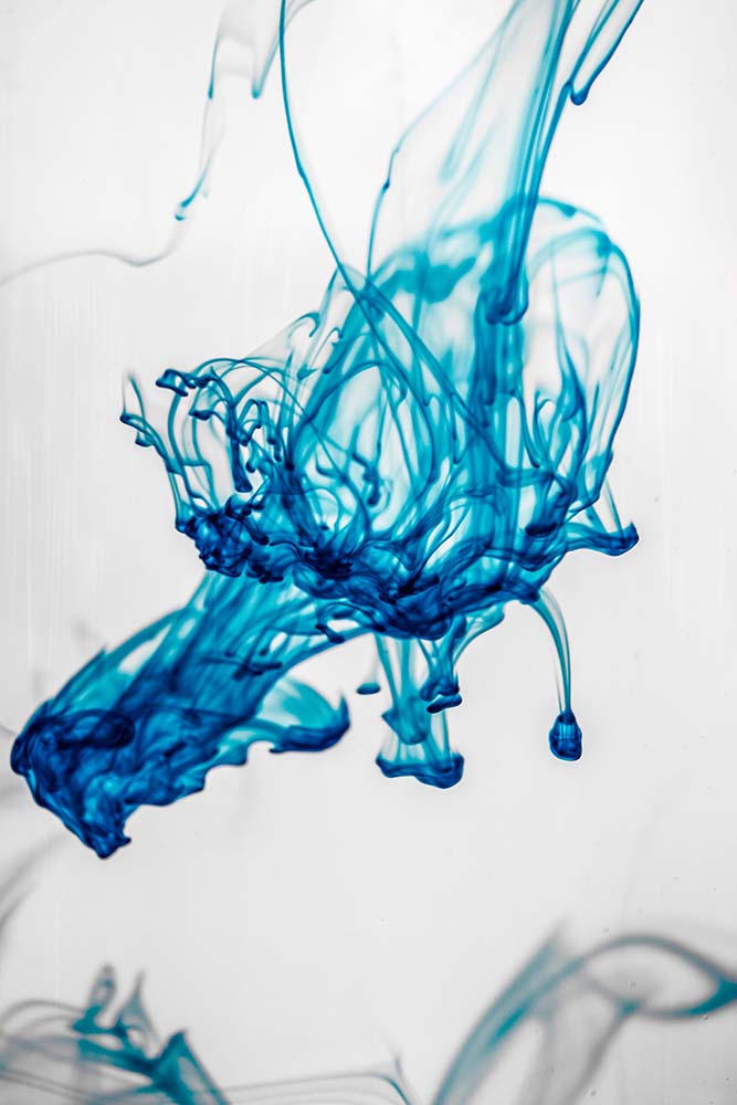 Blaue Tinte verteilt sich in Wasser in abstrakten Formen