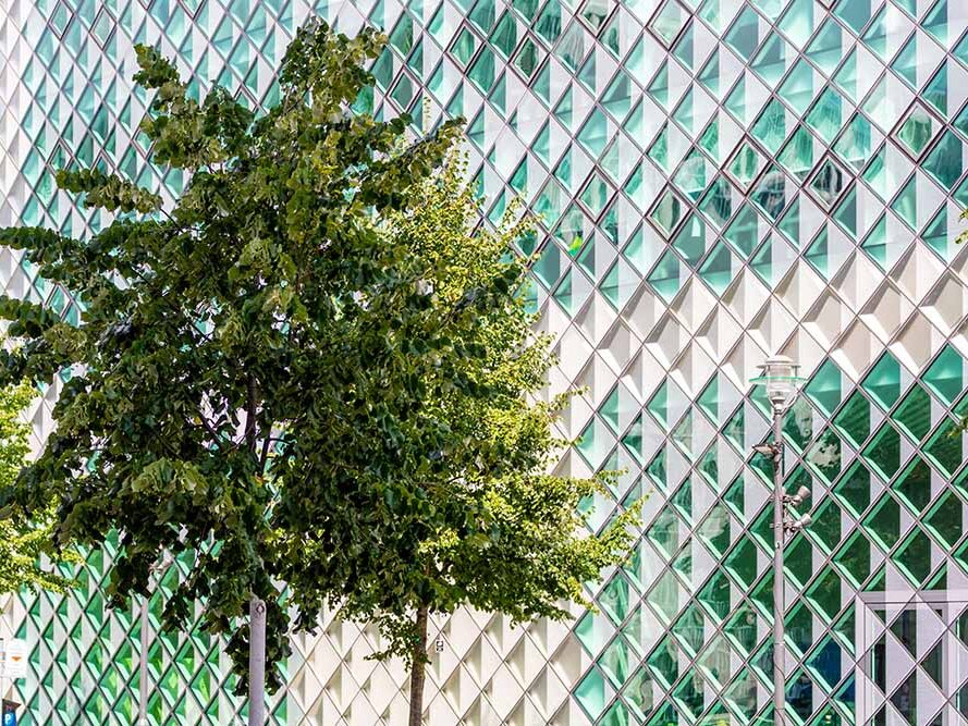 Diamond-shaped glass facade of the Futurium with trees in front of it