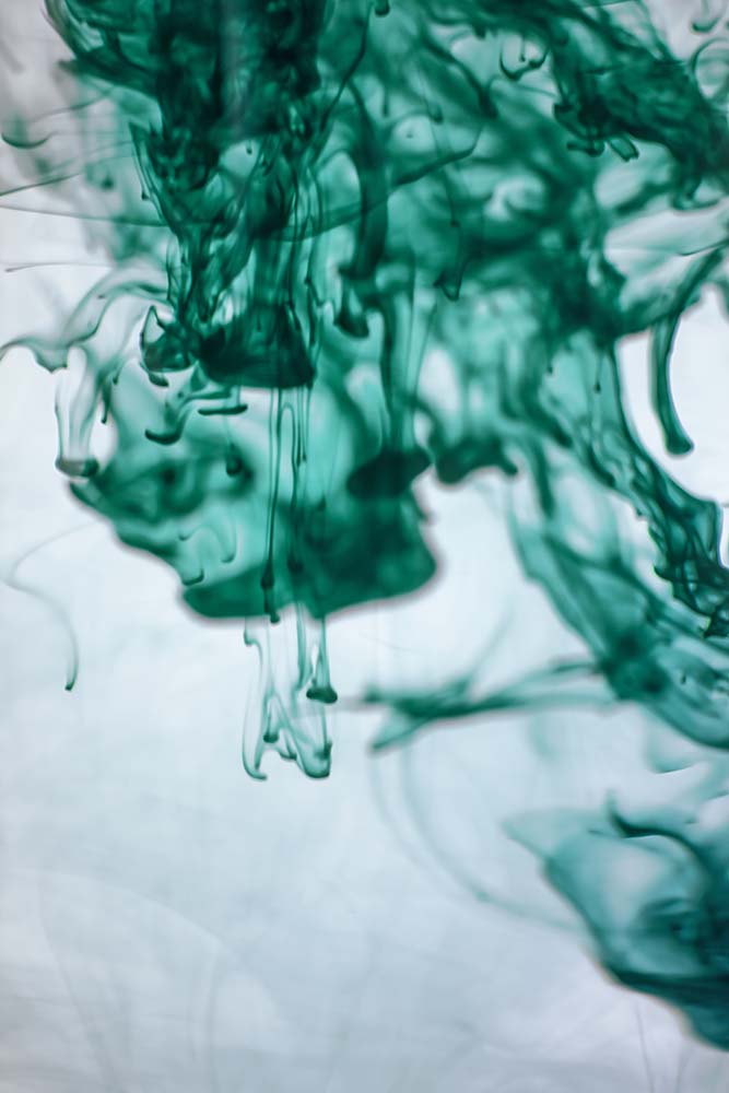 Grüne Tinte verteilt sich in Wasser in abstrakten Formen