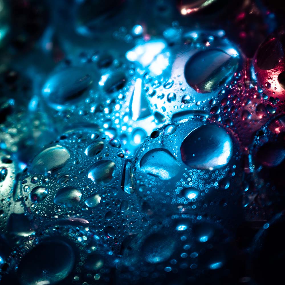 Wassertropfen auf dunkler, glänzender Kunststoffoberfläche