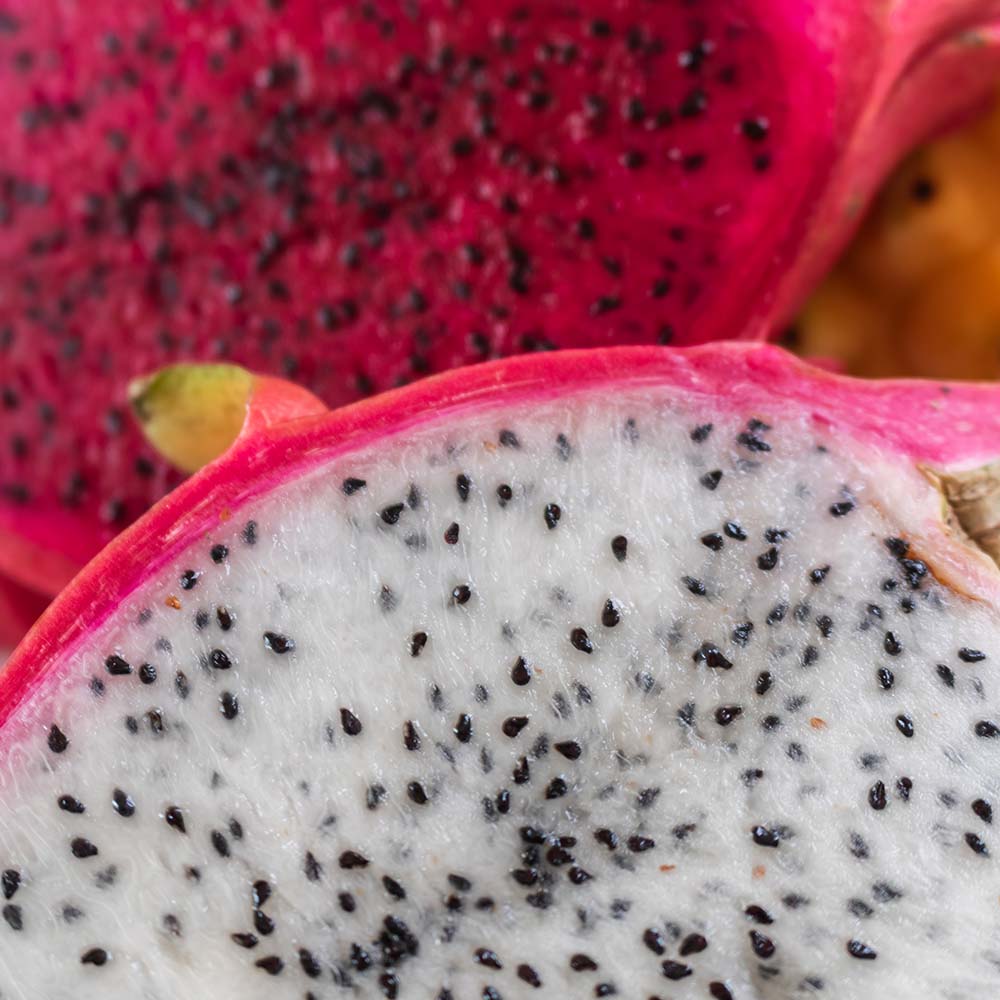 Makroaufnahme zweier aufgeschnittener Drachenfrüchte mit weißen und roten Innenflächen.