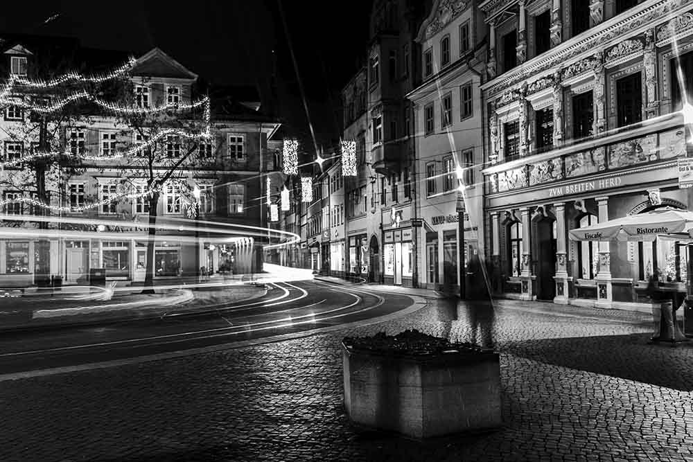 Langzeitbelichtung einer Straßenbahn am Erfurter Fischmarkt bei Nacht.