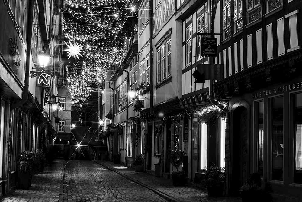 Schwarz‑weiß beleuchtete Krämerbrücke in Erfurt mit Weihnachtslichtern.