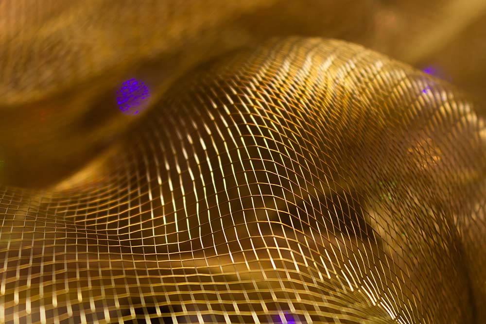 Golden schimmerndes Netzgewebe mit dynamischen, fließenden Strukturen.