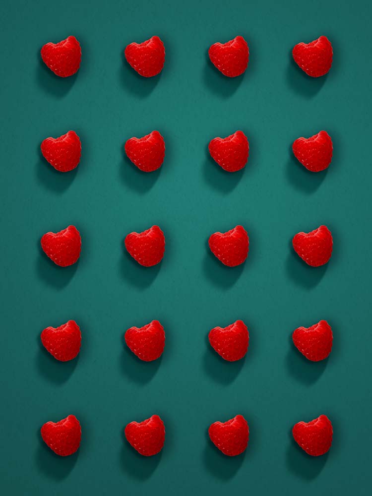 Mehrere Himbeeren in regelmäßigem Muster auf dunklem Hintergrund.