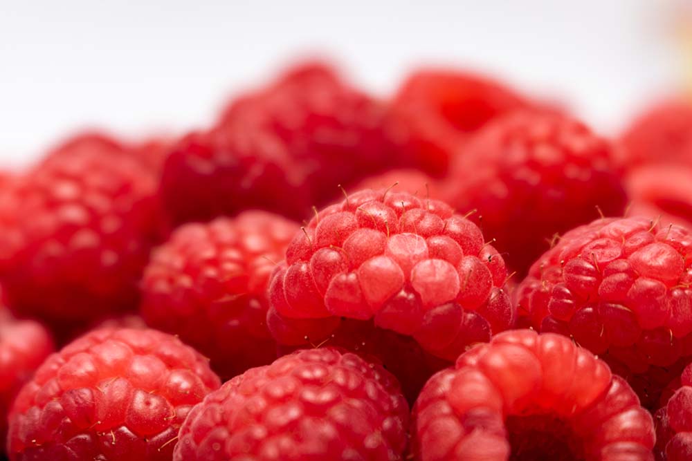 Makroaufnahme frischer, roter Himbeeren in natürlichem Licht.