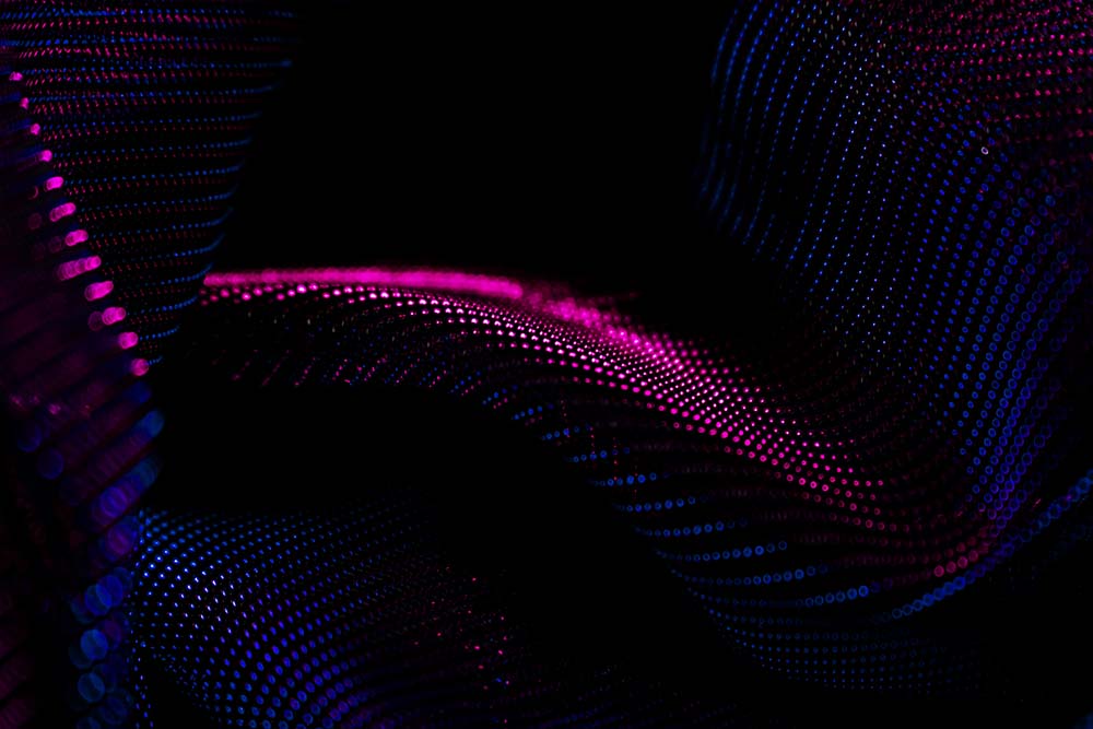 Abstrakte digitale Wellen aus pinken und blauen Lichtpunkten.