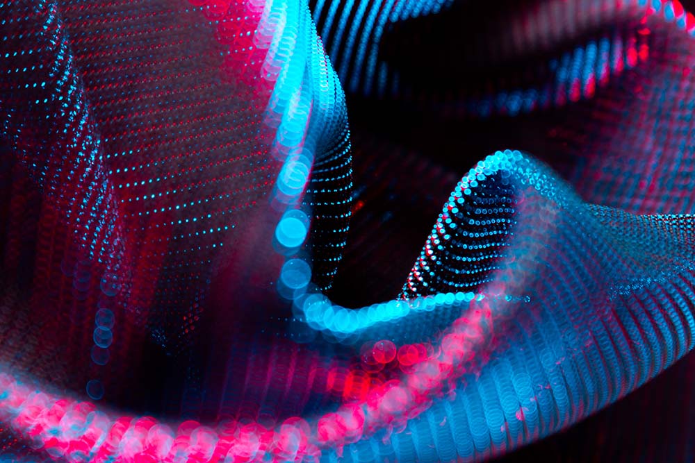 Abstrakte pink‑blaue Lichtpunktwellen in dynamischer Struktur.