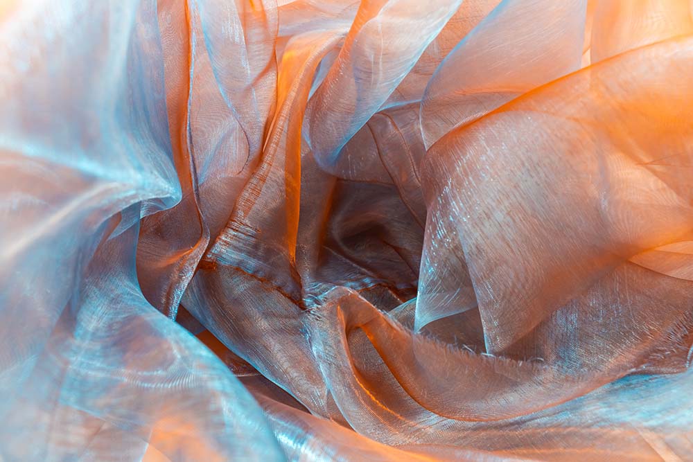 Transparente Organza‑Falten in Blau und Orange im Detail.