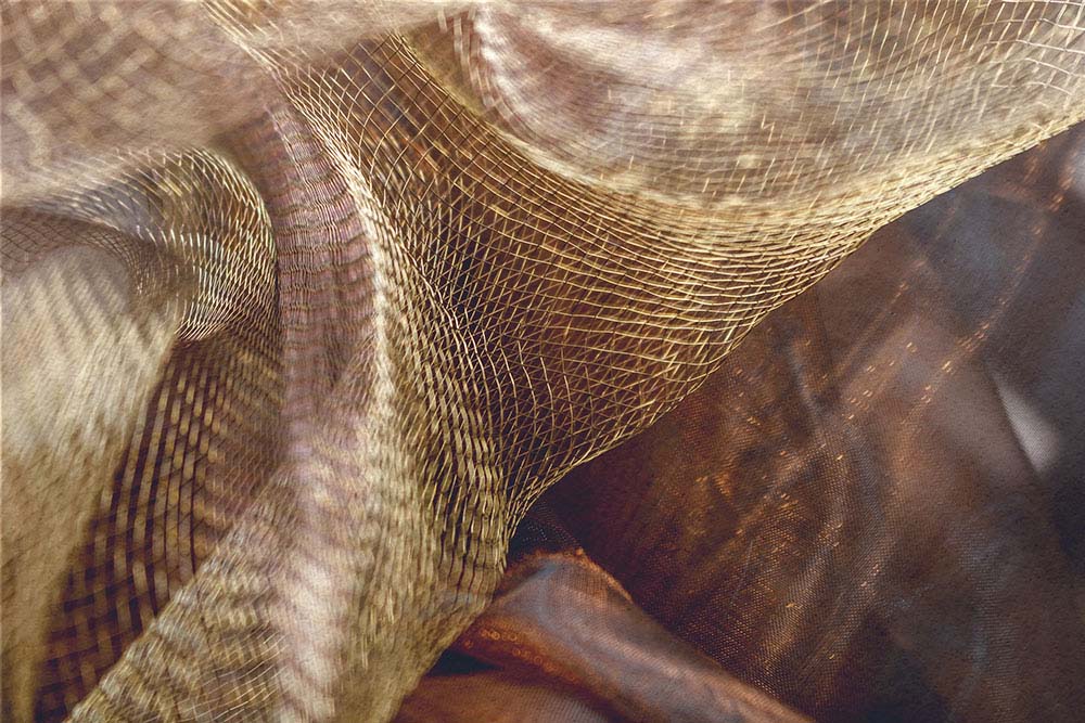 Golden schimmerndes Netz auf warmen Stofffalten in dynamischer Bewegung.