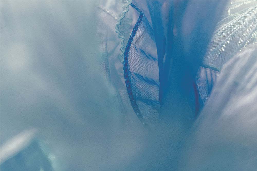 Transluzente blaue Stoffschichten mit feinen Nähten und weichen Übergängen.