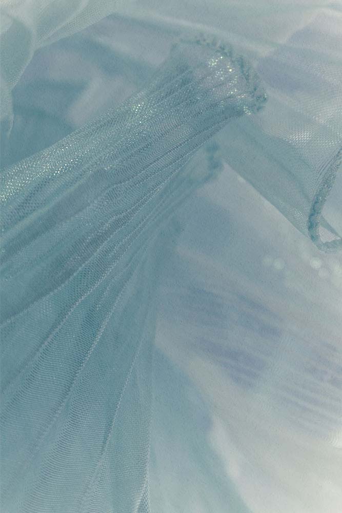 Zarter, hellblauer Organza‑Stoff in weichen, fließenden Falten.